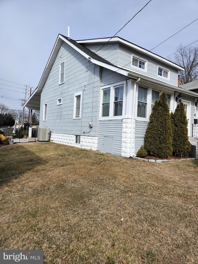 view of home's exterior with fence, cooling unit, and a yard