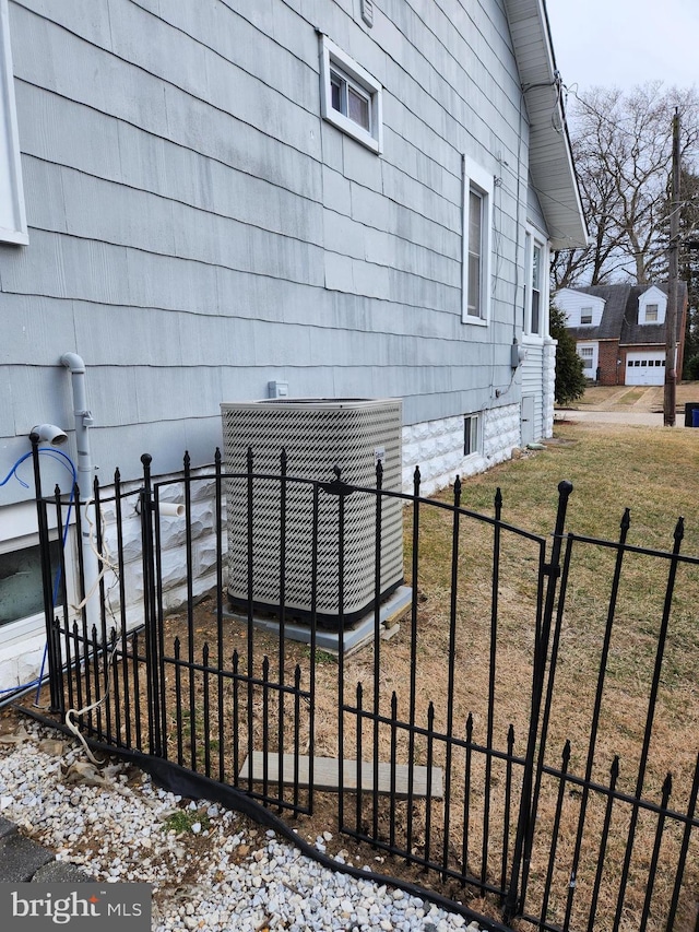 view of side of property featuring fence, central AC, and a yard