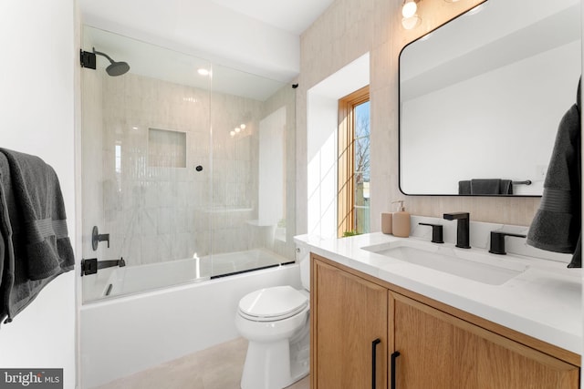 full bath featuring combined bath / shower with glass door, vanity, and toilet