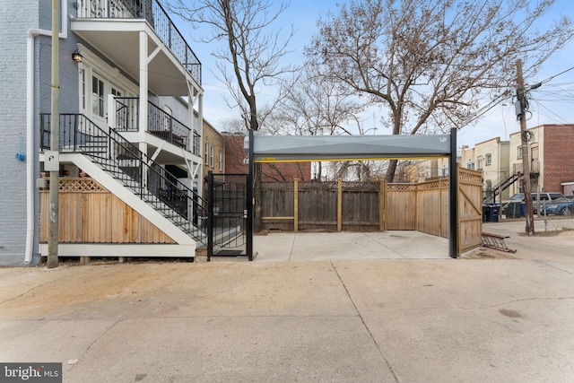 view of patio / terrace with a carport, fence, and stairs