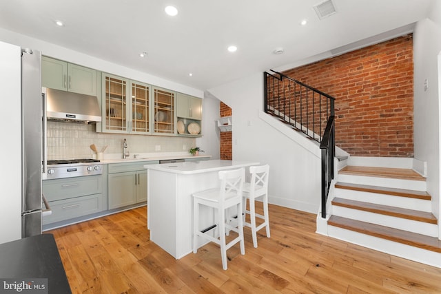 kitchen with green cabinetry, light wood-style floors, stainless steel appliances, and under cabinet range hood