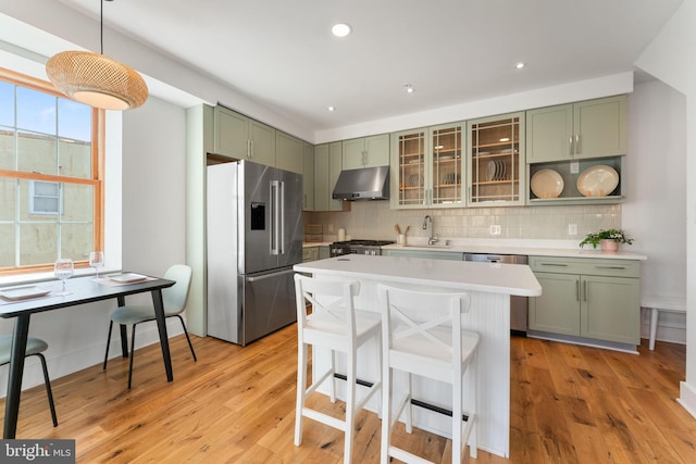 kitchen with stainless steel appliances, light countertops, green cabinetry, and under cabinet range hood