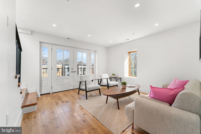 living area featuring baseboards, light wood finished floors, visible vents, and recessed lighting