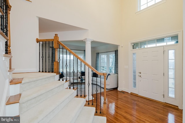 entryway featuring decorative columns, stairway, and wood finished floors