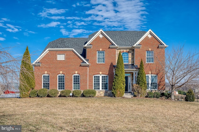 view of front of house featuring brick siding, a front lawn, and a shingled roof