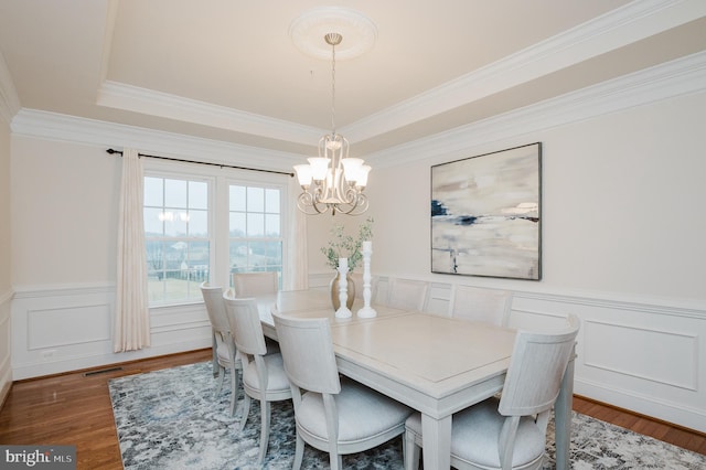 dining area featuring wainscoting, wood finished floors, visible vents, and crown molding