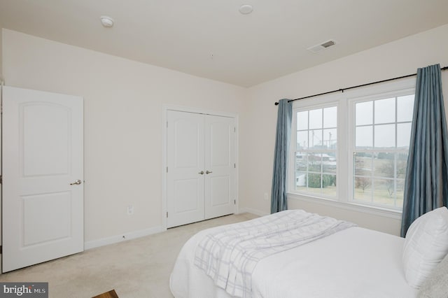 bedroom with light carpet, baseboards, visible vents, and a closet