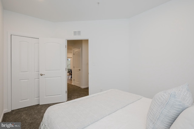 bedroom with a closet, dark carpet, and visible vents