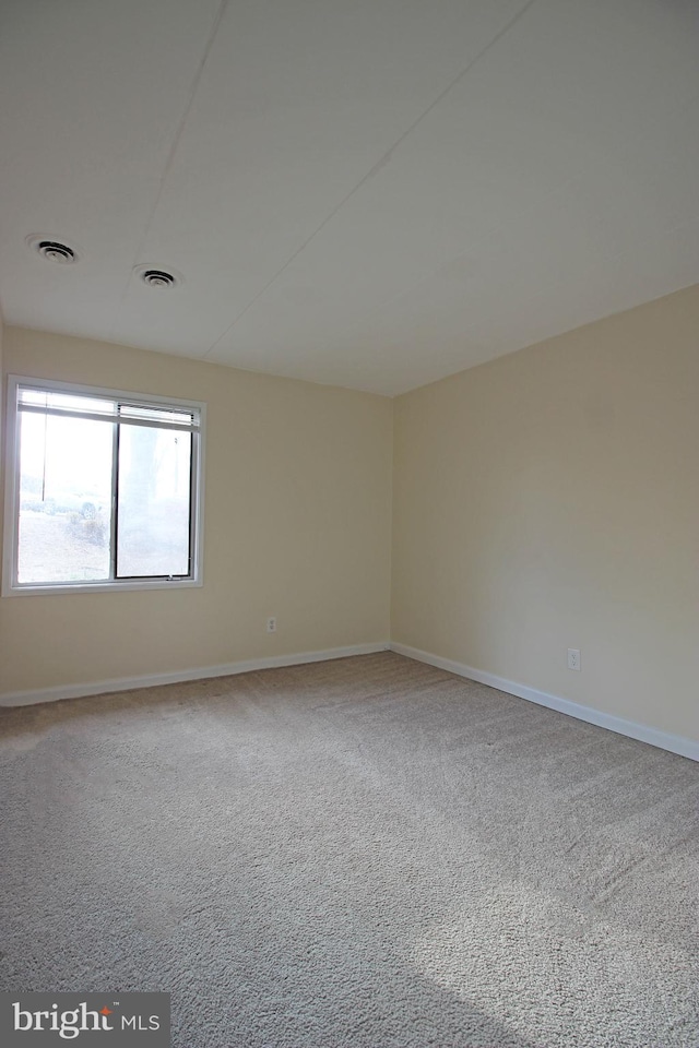 unfurnished room with carpet flooring, visible vents, and baseboards