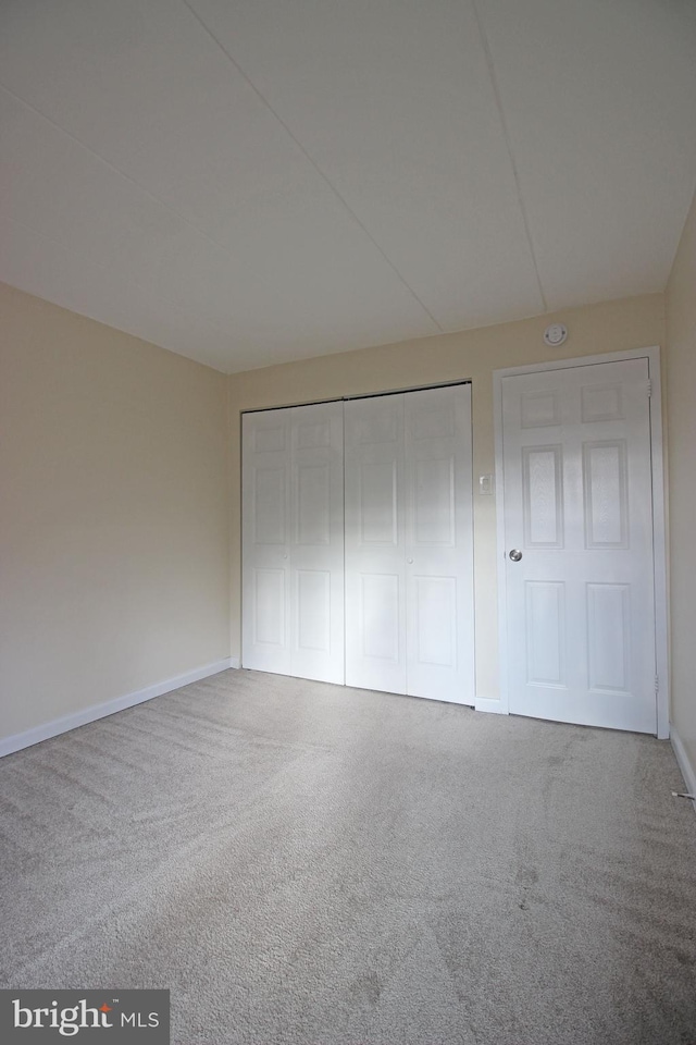 unfurnished bedroom with a closet, carpet, and baseboards