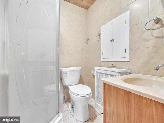 full bathroom featuring tile walls, toilet, vanity, a shower stall, and tile patterned floors