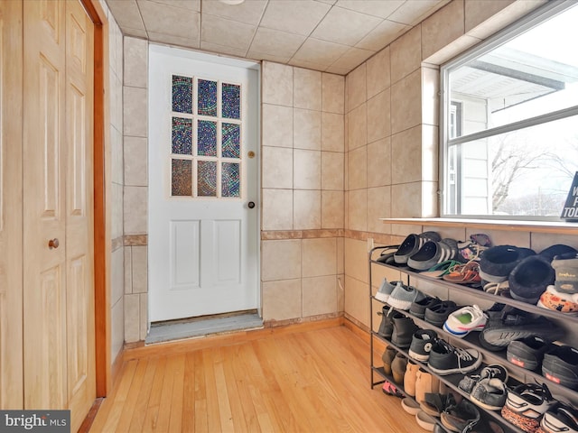 doorway to outside with light wood finished floors and tile walls