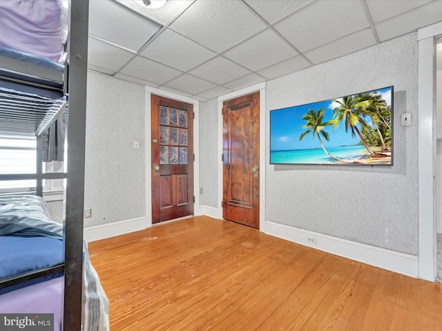 entryway featuring a paneled ceiling, a textured wall, baseboards, and wood finished floors