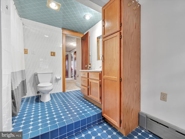 full bath featuring tile walls, toilet, baseboard heating, vanity, and tile patterned floors