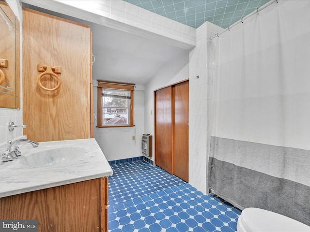 full bath featuring lofted ceiling, toilet, heating unit, curtained shower, and vanity