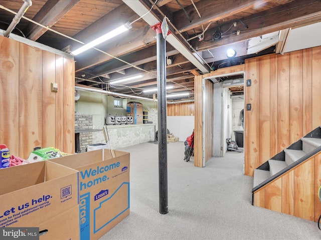 unfinished basement featuring carpet, wood walls, and stairs