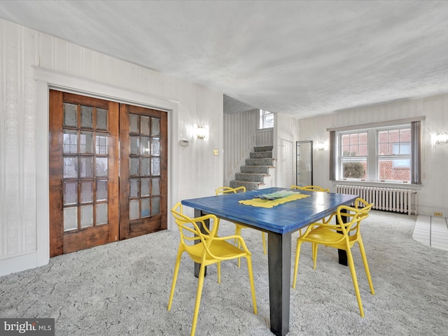 dining space featuring french doors, stairway, radiator heating unit, and carpet flooring