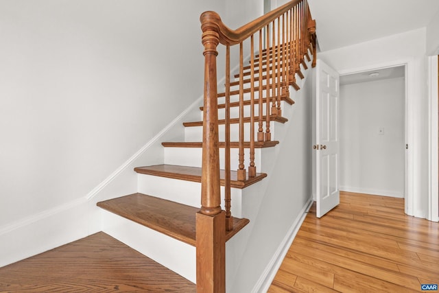 staircase featuring baseboards and wood finished floors