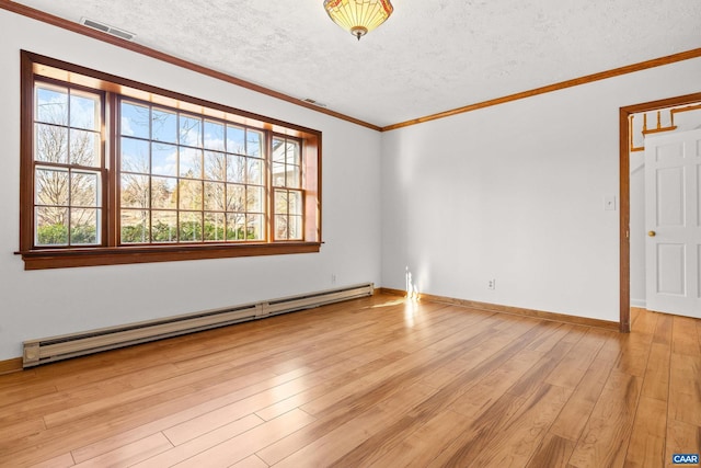 spare room featuring a baseboard heating unit, plenty of natural light, visible vents, and light wood-style floors