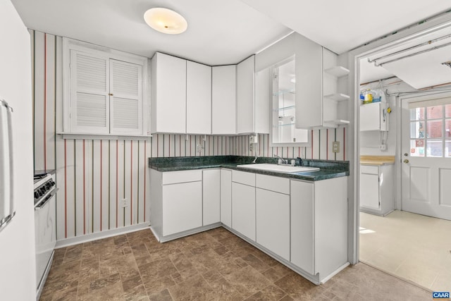 kitchen featuring dark countertops, white cabinetry, open shelves, and a sink