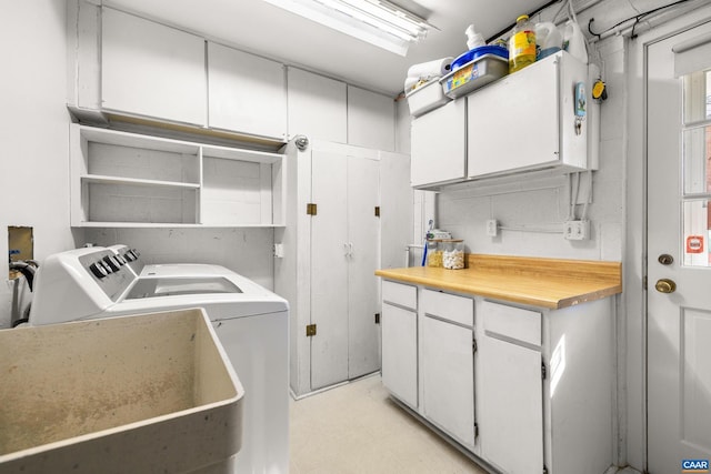 laundry room featuring light floors, washer and clothes dryer, a sink, and cabinet space