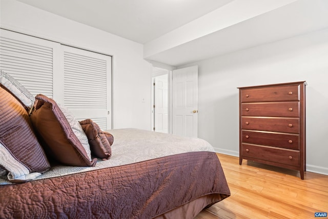 bedroom featuring light wood-style floors, baseboards, and a closet