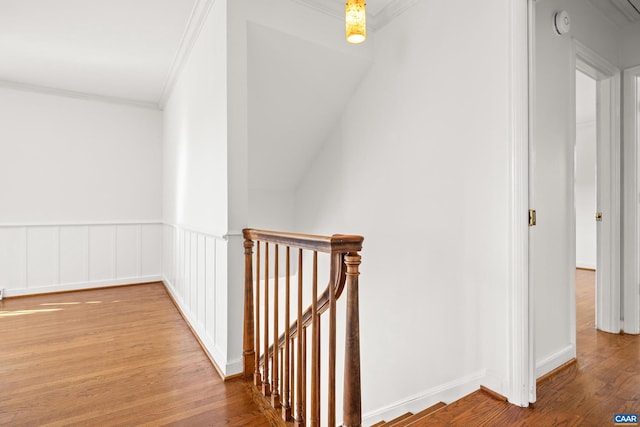 hall featuring ornamental molding, wainscoting, an upstairs landing, and wood finished floors