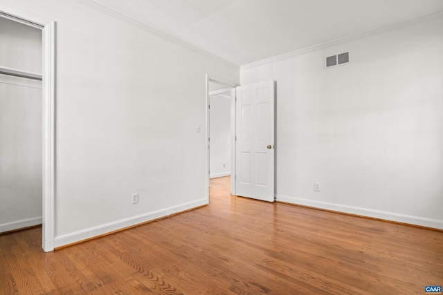 unfurnished bedroom with baseboards, wood finished floors, visible vents, and crown molding