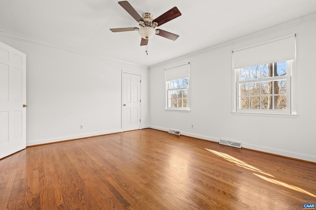 unfurnished room featuring baseboards, wood finished floors, visible vents, and crown molding