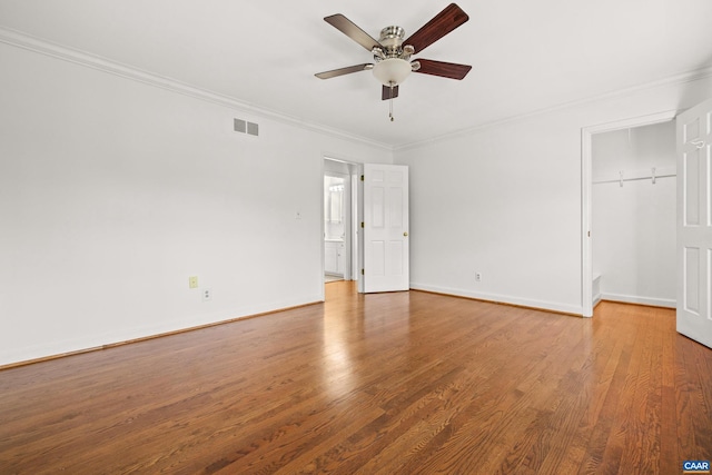 unfurnished bedroom featuring wood finished floors, visible vents, baseboards, a closet, and crown molding