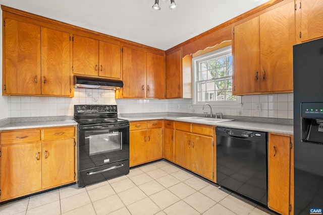 kitchen with brown cabinetry, light countertops, under cabinet range hood, and black appliances