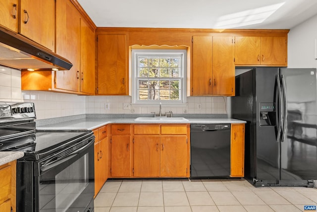 kitchen featuring under cabinet range hood, a sink, light countertops, decorative backsplash, and black appliances