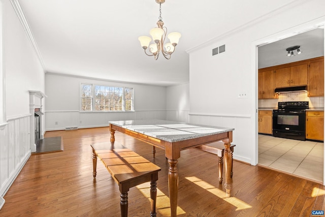 dining room with light wood-style floors, visible vents, a chandelier, and wainscoting