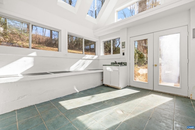 unfurnished sunroom featuring lofted ceiling with skylight and french doors