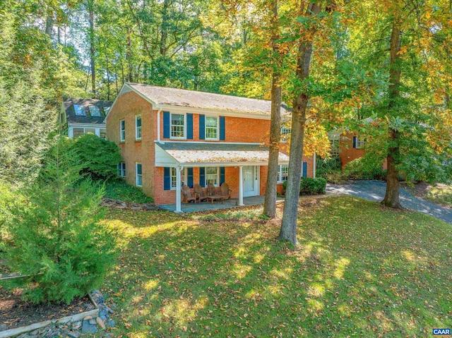 view of front of home with a porch, brick siding, and a front lawn