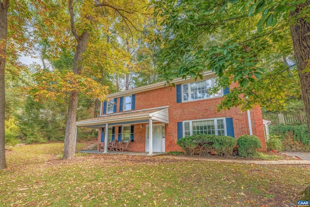 view of front of house featuring brick siding, a front lawn, and a porch