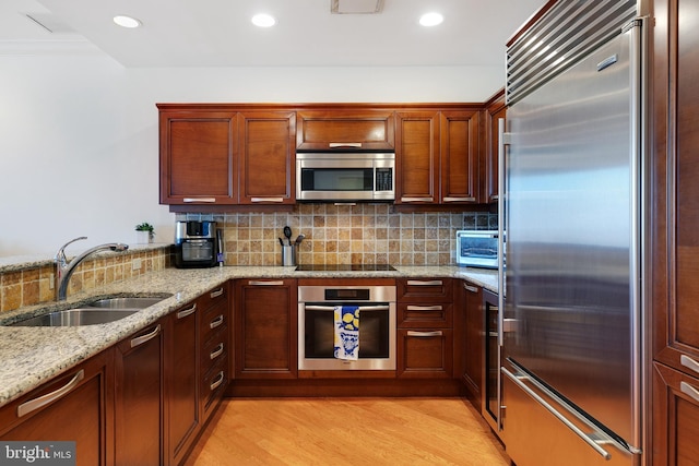 kitchen with light stone countertops, tasteful backsplash, stainless steel appliances, and a sink