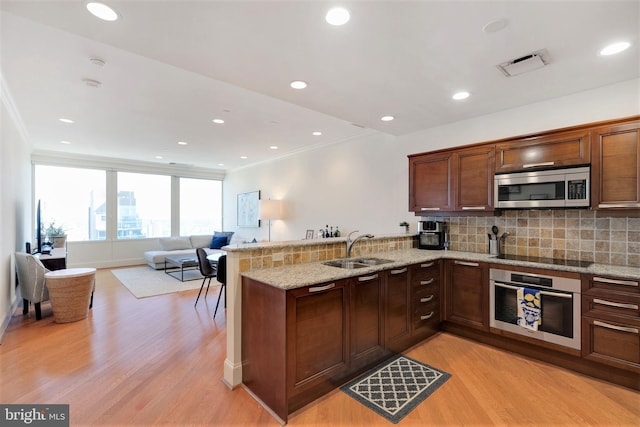 kitchen featuring a peninsula, appliances with stainless steel finishes, open floor plan, and a sink