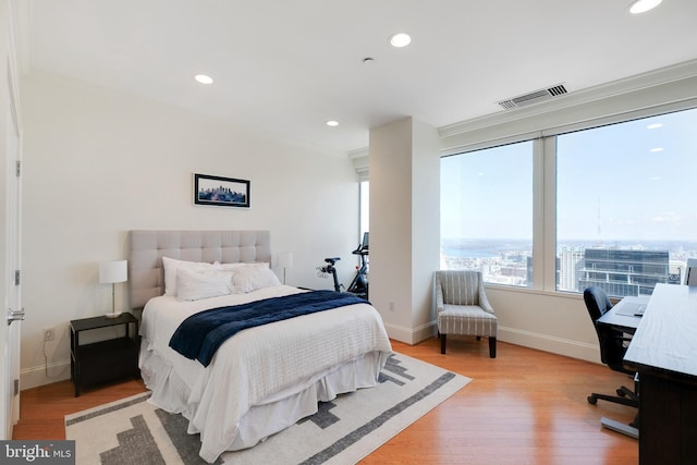 bedroom featuring a city view, recessed lighting, visible vents, wood finished floors, and baseboards