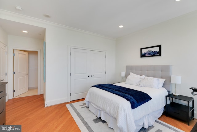 bedroom featuring ornamental molding, a closet, light wood-type flooring, and baseboards