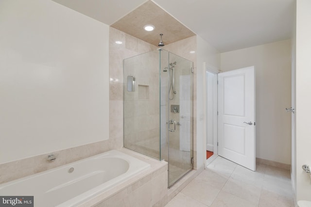 bathroom featuring a stall shower, tile patterned flooring, a garden tub, and baseboards