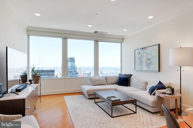 living room featuring a healthy amount of sunlight, a city view, crown molding, and visible vents