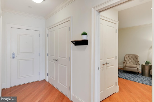 corridor with baseboards, ornamental molding, and wood finished floors