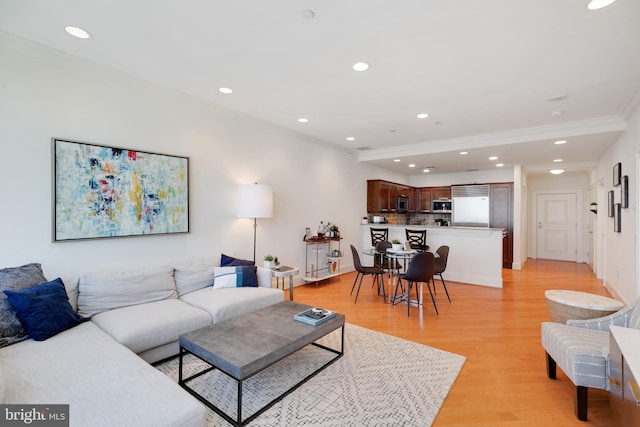 living area with crown molding, light wood-type flooring, baseboards, and recessed lighting