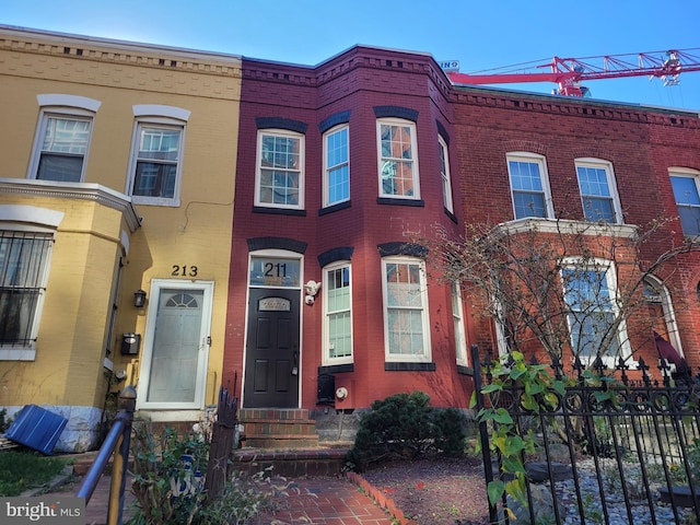 view of property featuring entry steps, brick siding, and fence