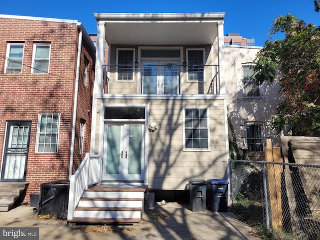 rear view of house with fence and a balcony