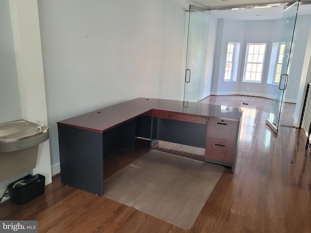 unfurnished office featuring baseboards and wood finished floors