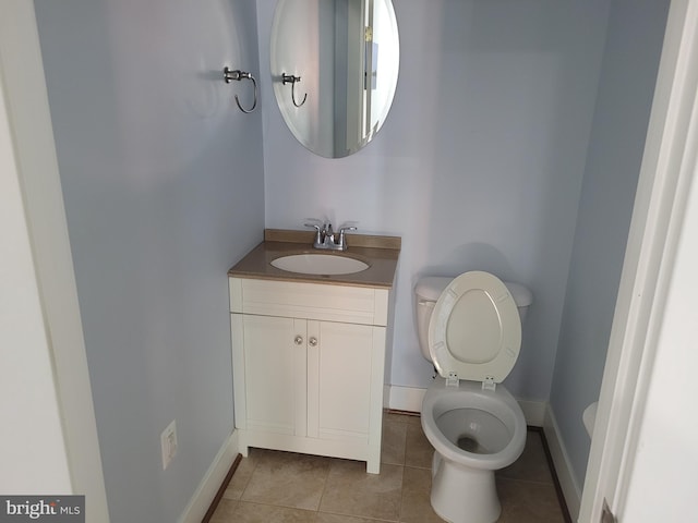 bathroom with tile patterned flooring, baseboards, vanity, and toilet