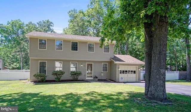 colonial inspired home featuring aphalt driveway, a front yard, fence, and an attached garage