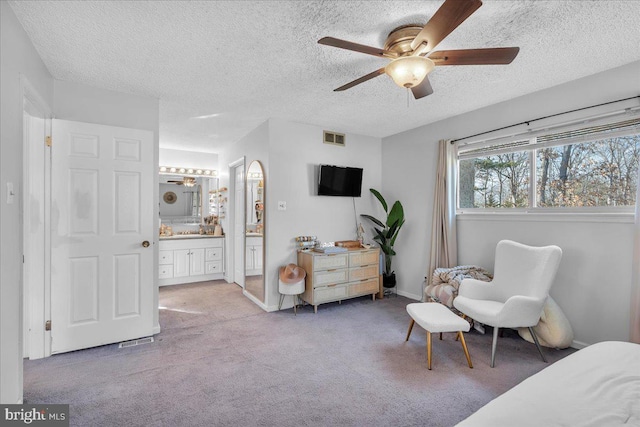 bedroom featuring visible vents, a ceiling fan, connected bathroom, a textured ceiling, and carpet floors